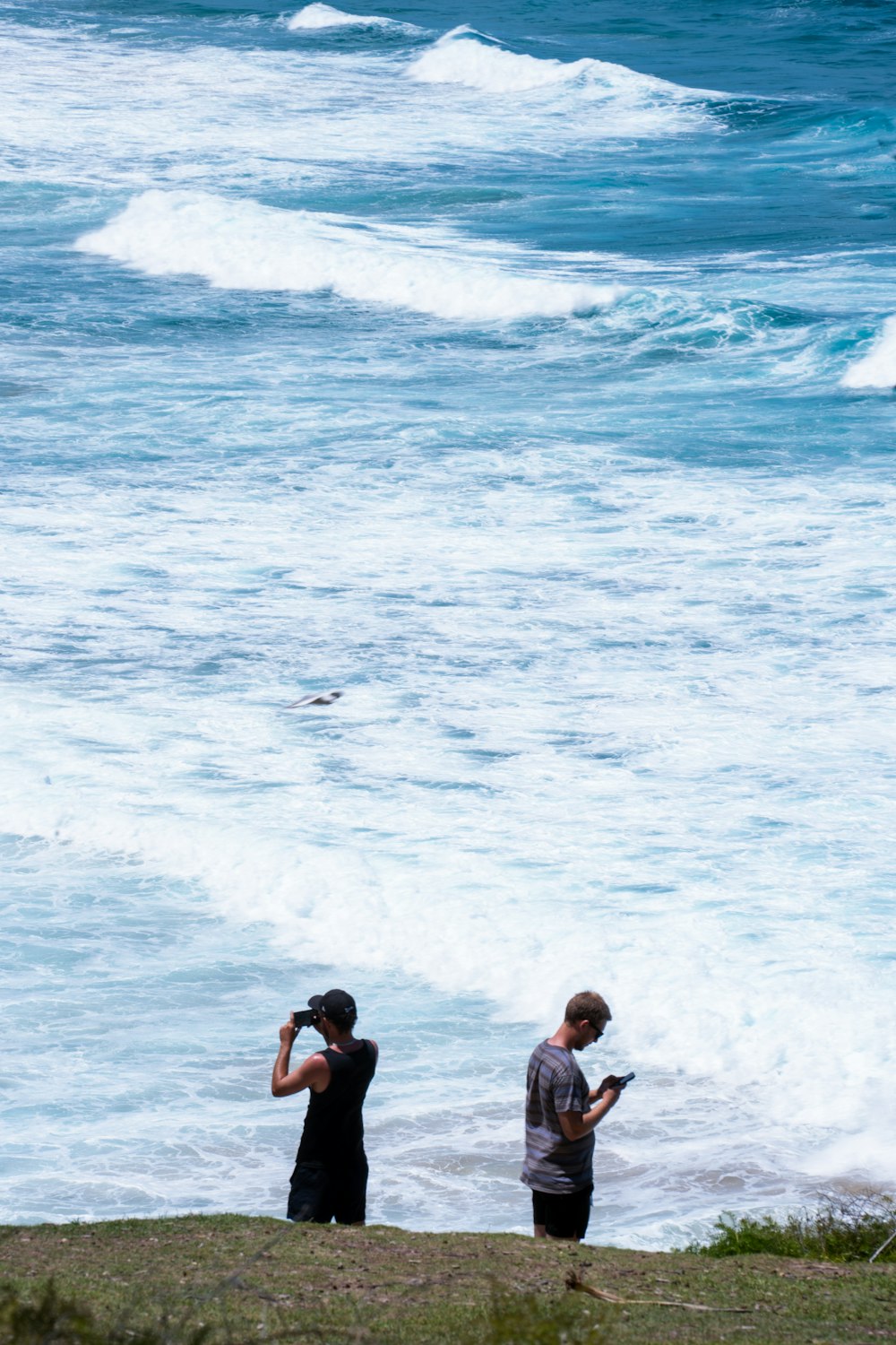 a couple of people standing on top of a beach next to the ocean