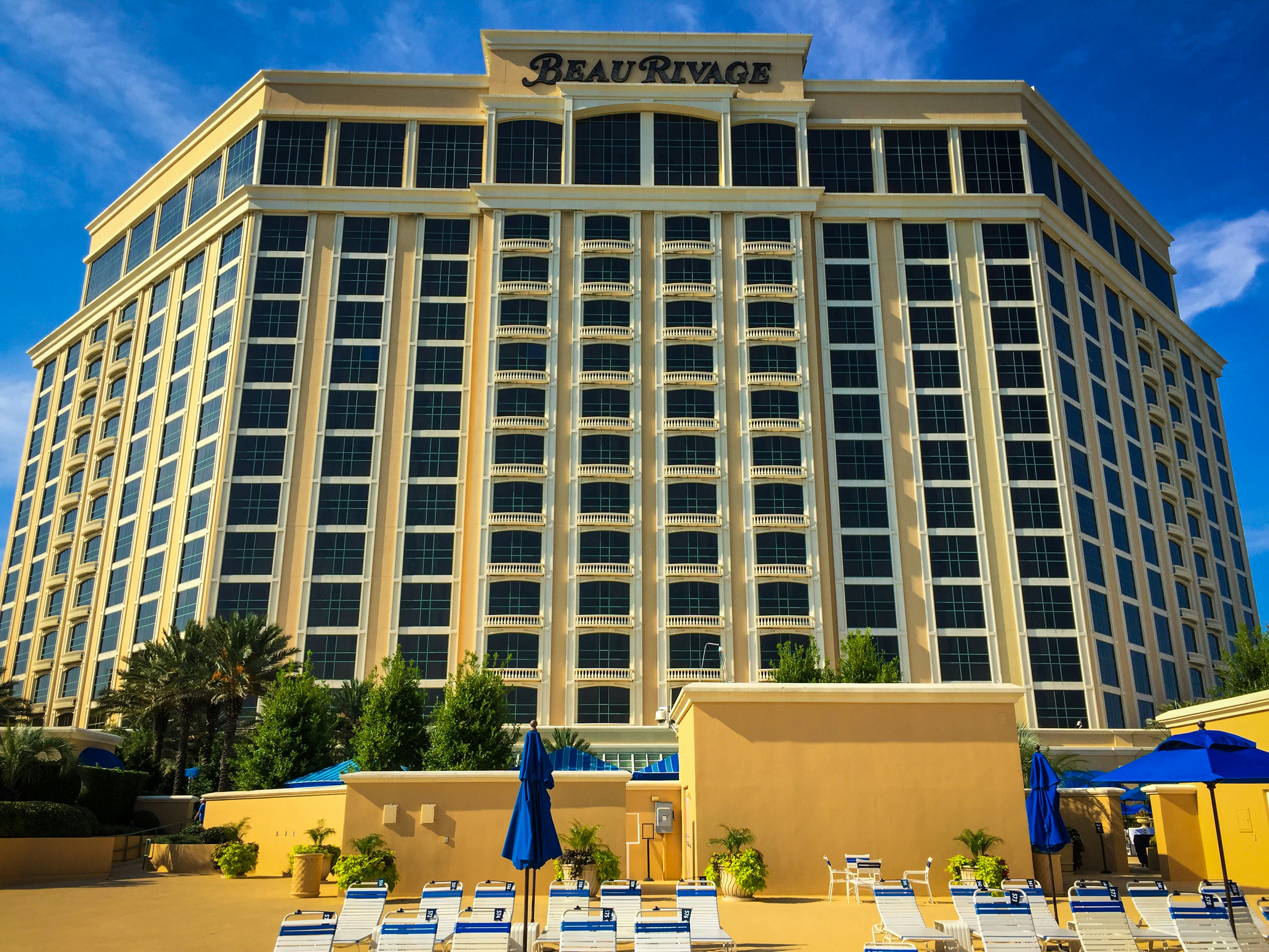 a large building with a lot of chairs and umbrellas in front of it