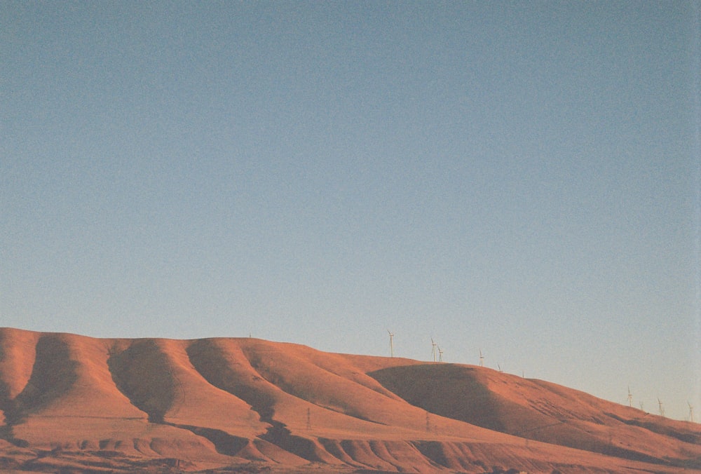 a plane flying over a hill covered in sand