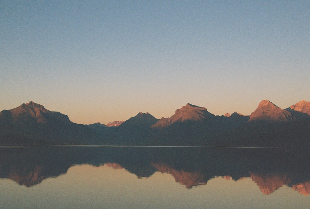 the mountains are reflected in the still water of the lake