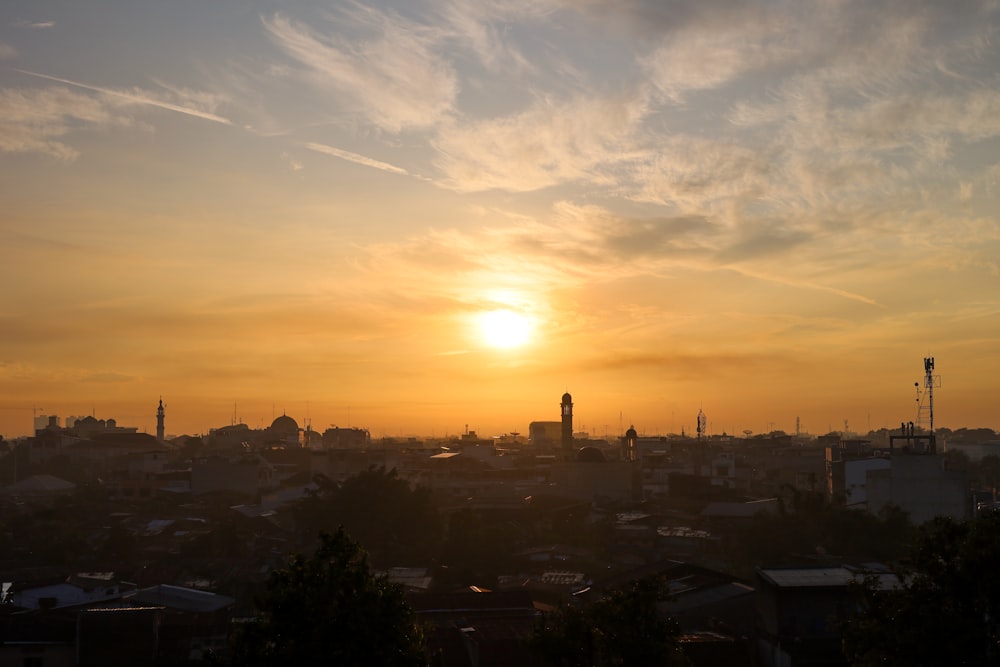 the sun is setting over a city with tall buildings