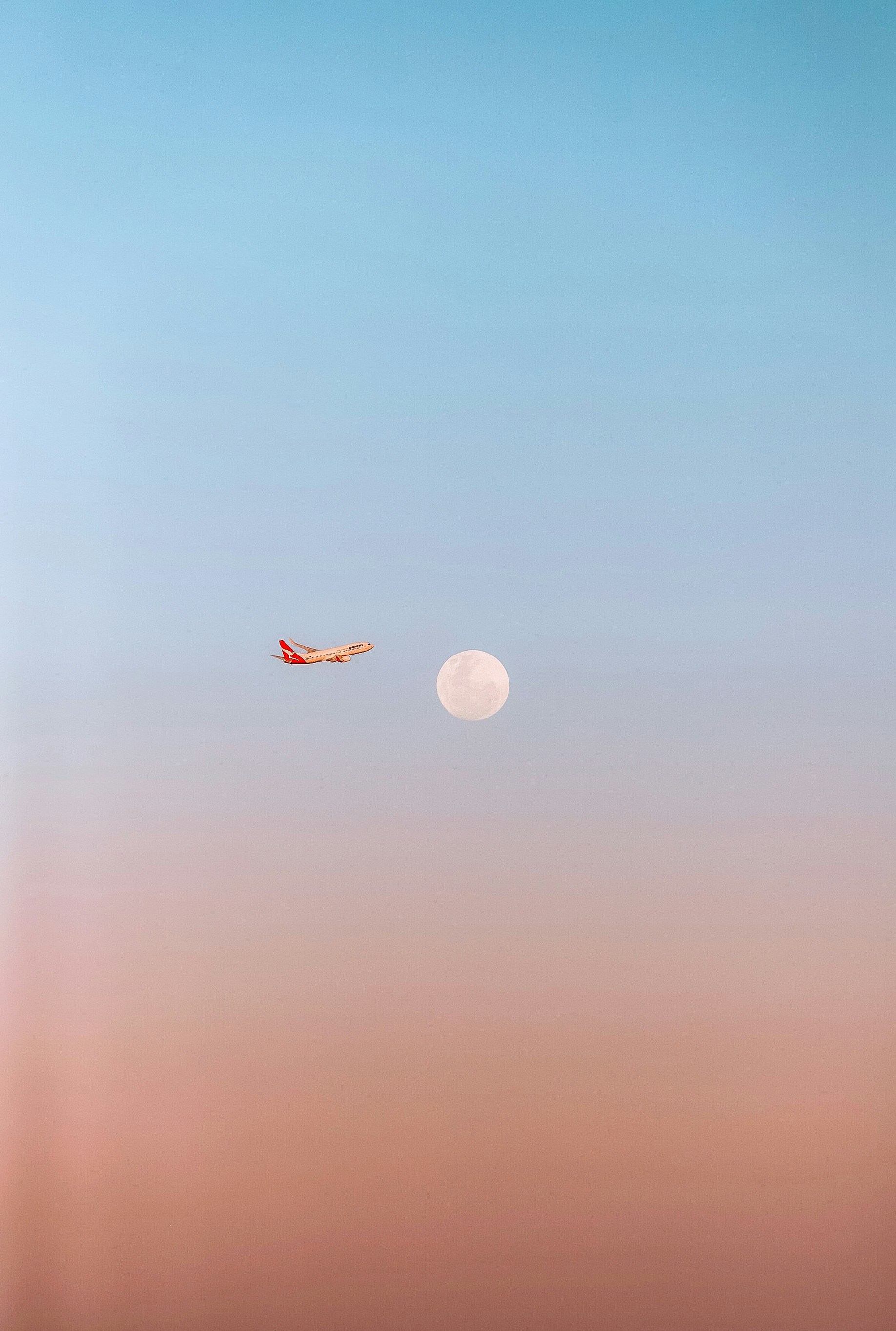 um avião voando no céu com uma lua ao fundo