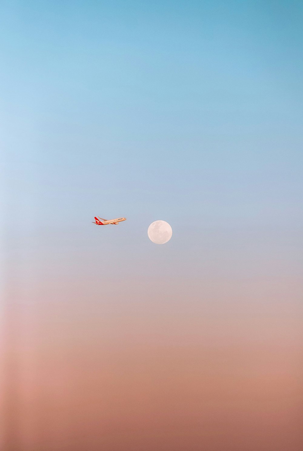 an airplane flying in the sky with a moon in the background