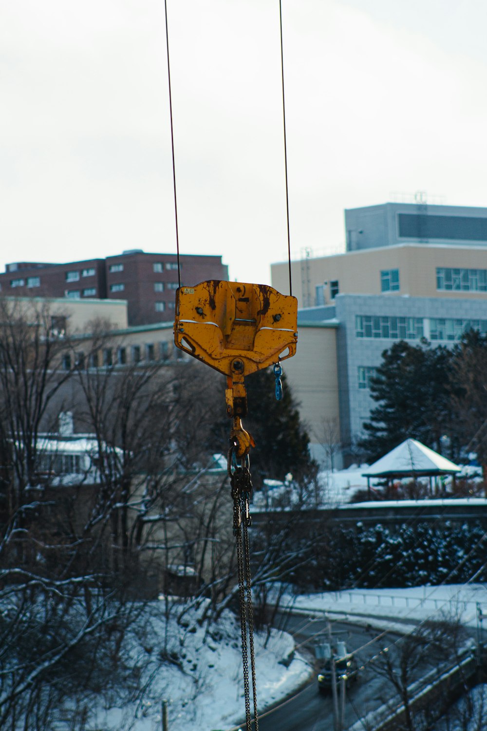 a yellow crane is hanging from a wire