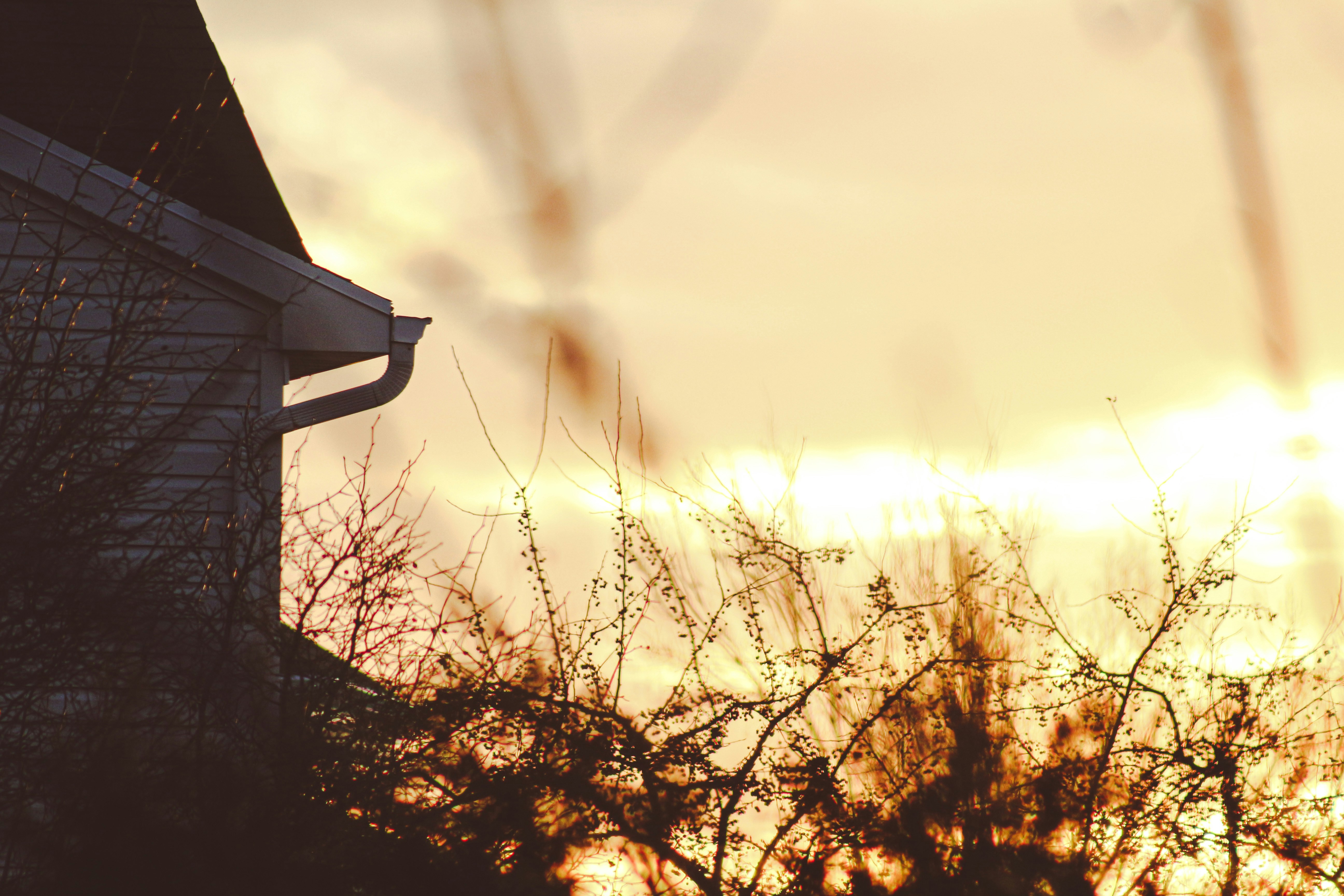 the sun is setting behind a house with a roof