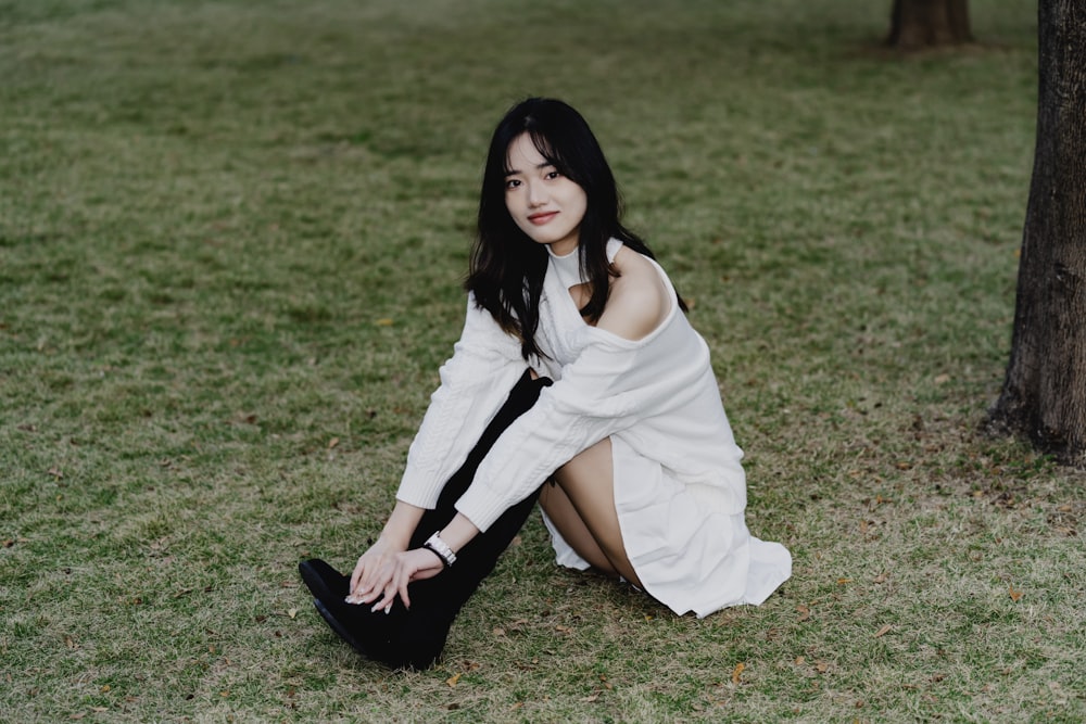 a woman in a white dress sitting on the grass