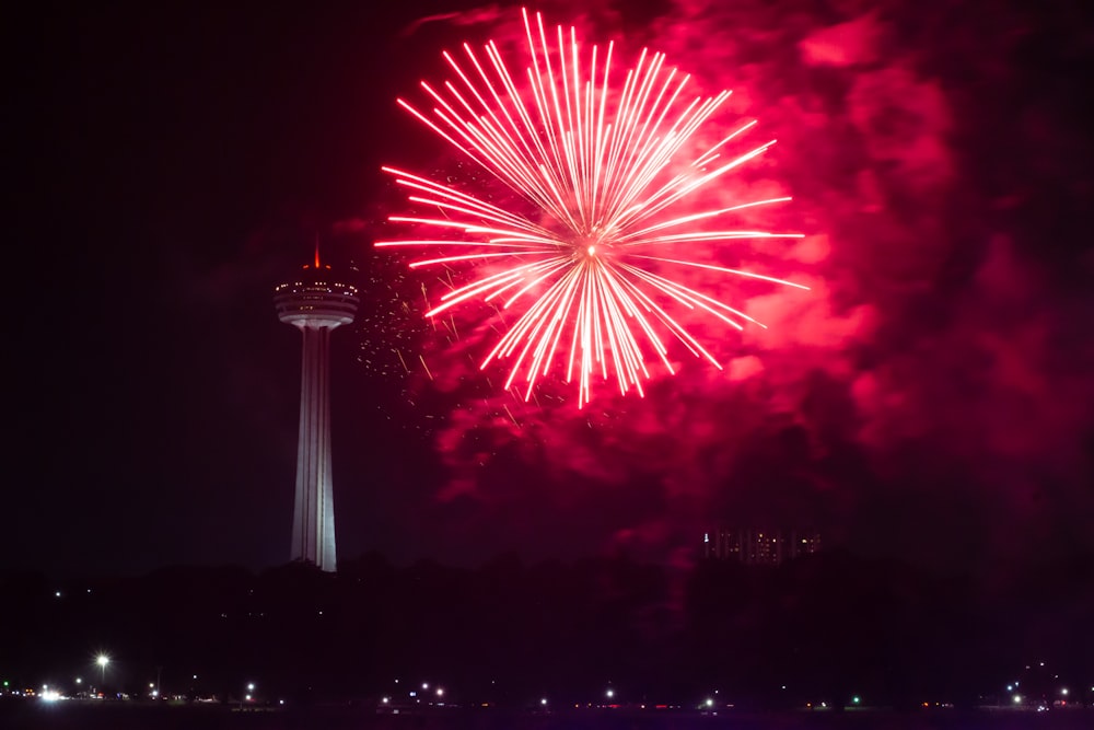 ein Feuerwerk am Nachthimmel mit einem Turm im Hintergrund