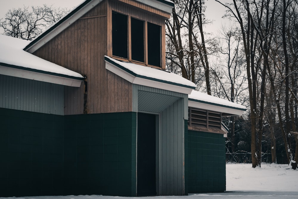 a building with a snow covered roof next to a forest