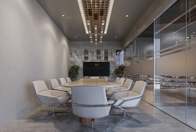 a conference room with a round table surrounded by white chairs