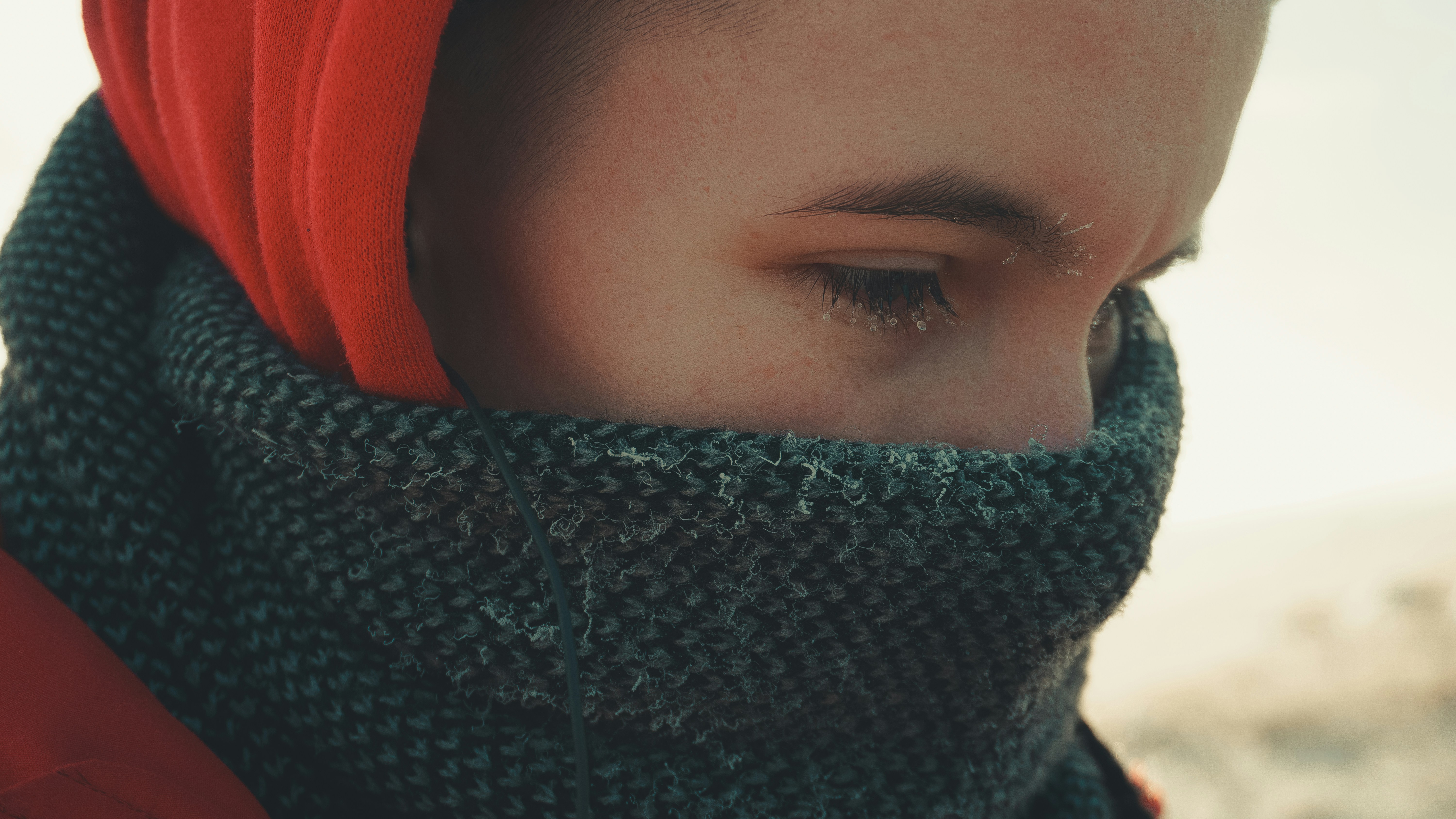 Person wrapped in a scarf looking down in the cold.
