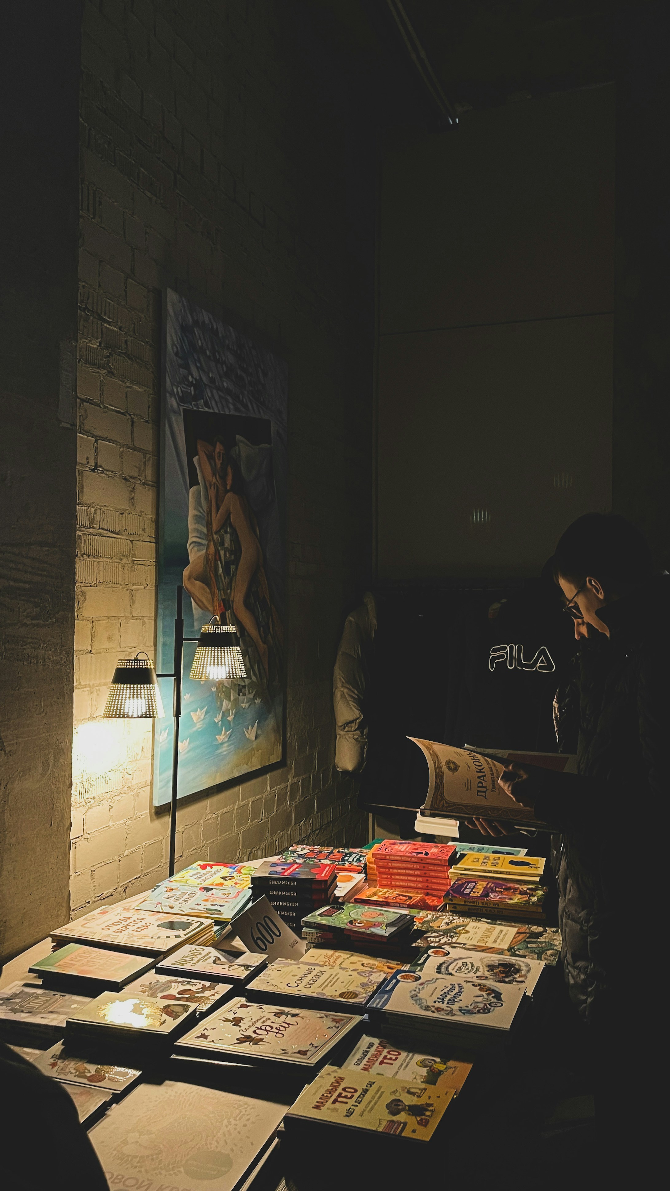Person browsing books at a dimly lit bookstall.