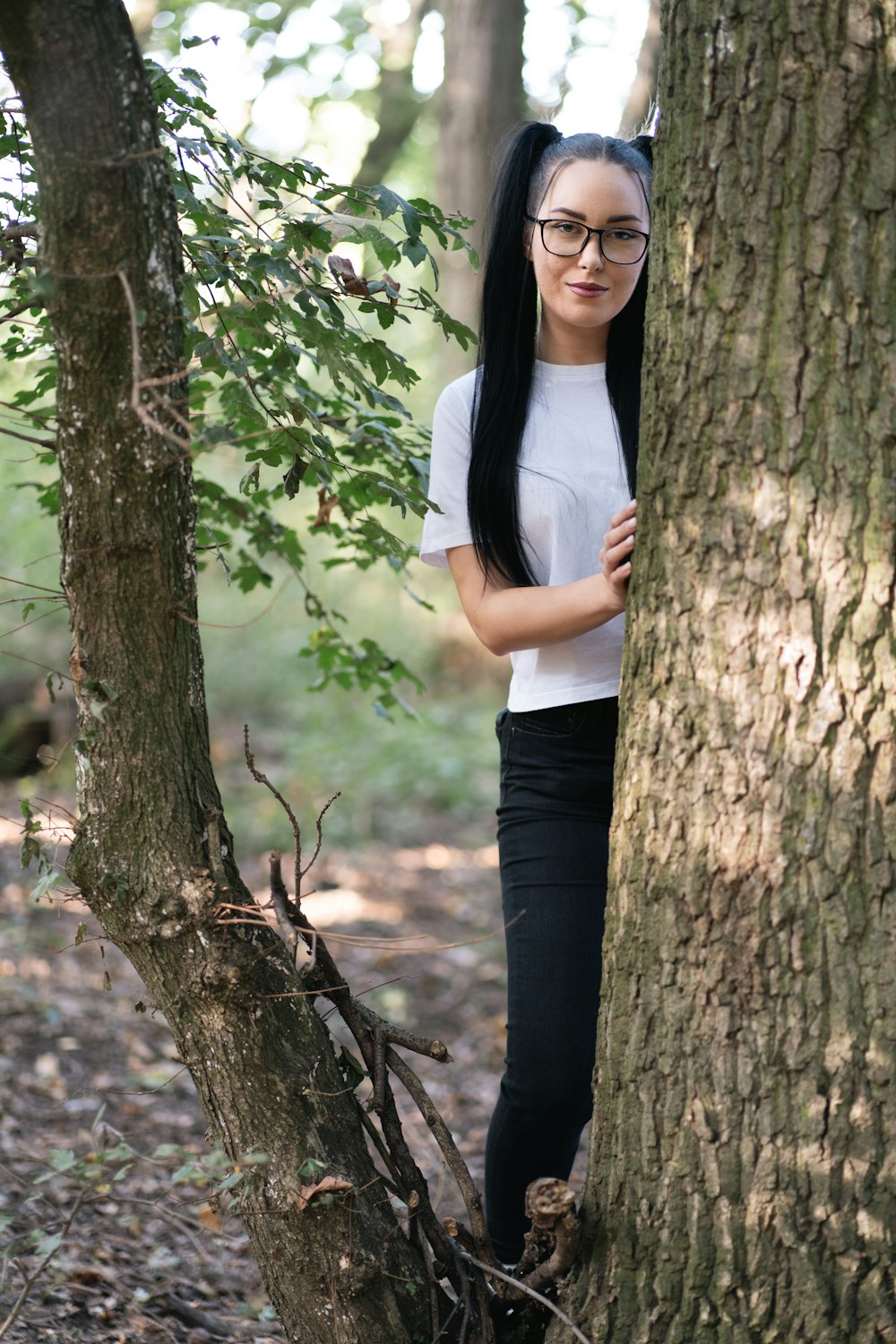 a woman with long black hair standing next to a tree