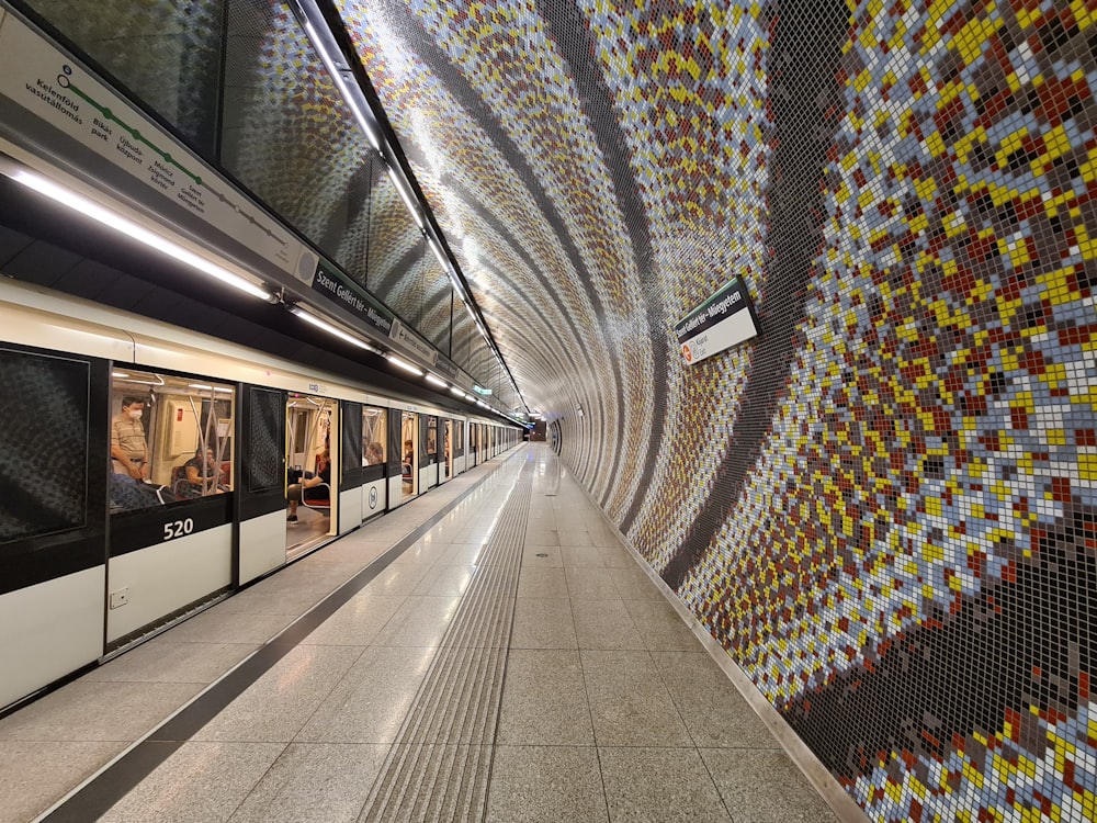 eine U-Bahn-Station mit einer mit Mosaikfliesen verkleideten Wand