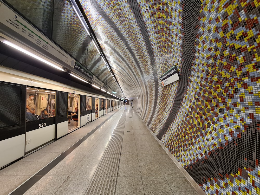 una estación de metro con una pared cubierta de mosaicos