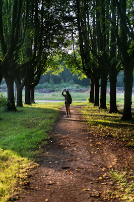 a person walking down a dirt path between trees