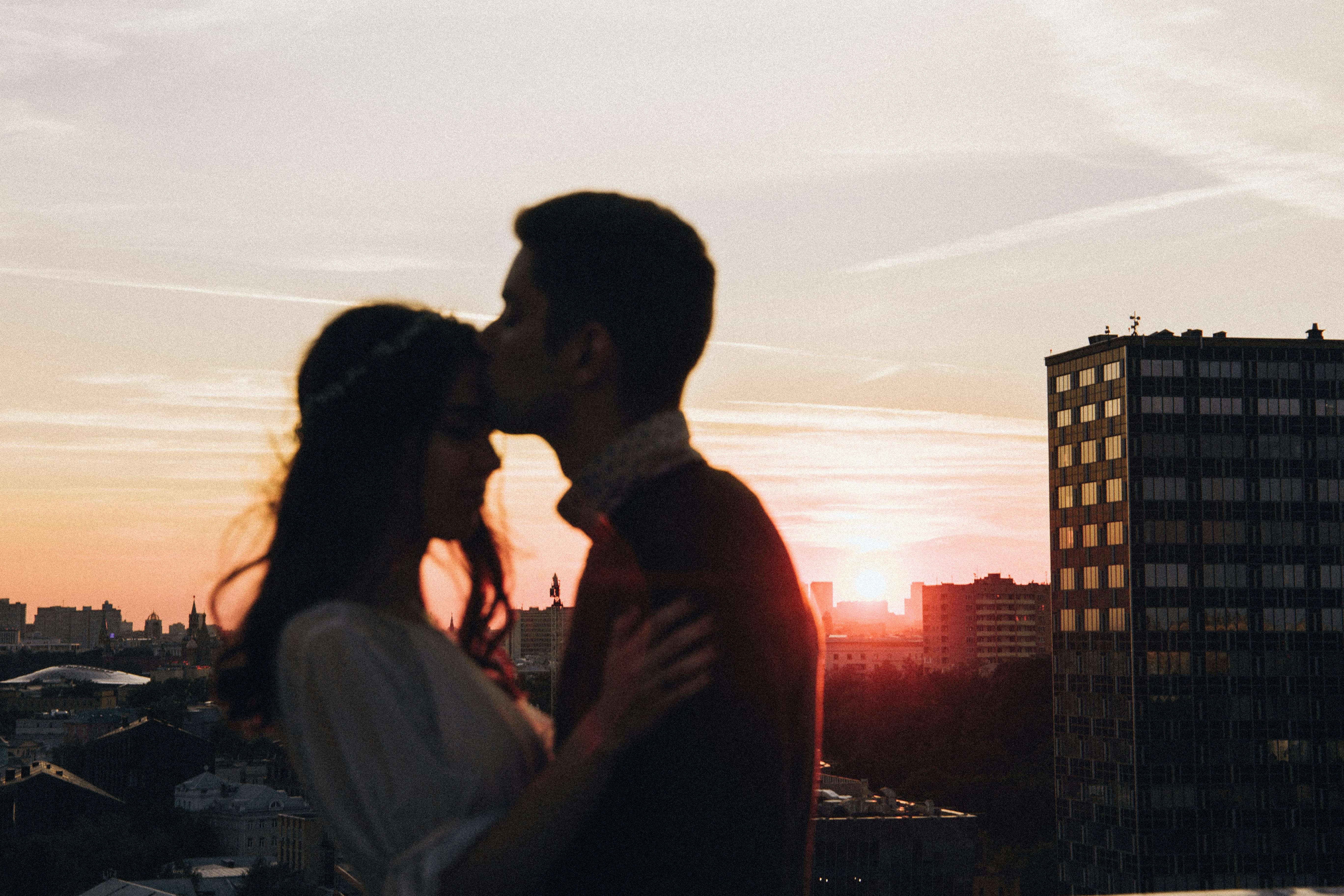 a man and a woman kissing in front of a sunset