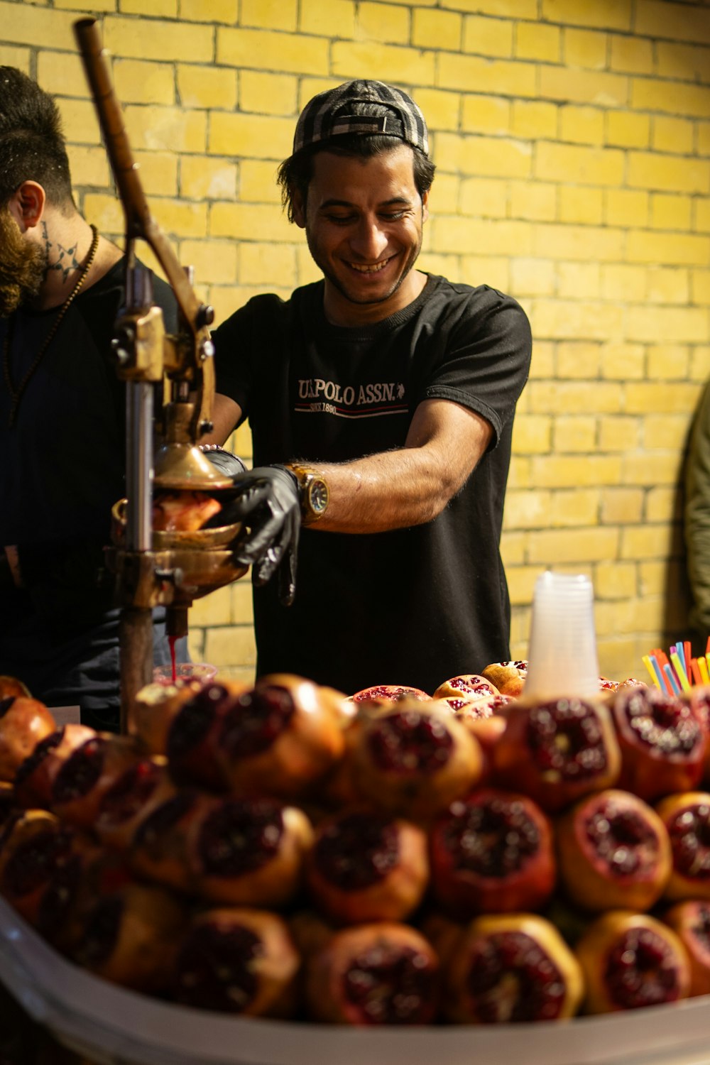 a man working on a machine in front of a pile of doughnuts