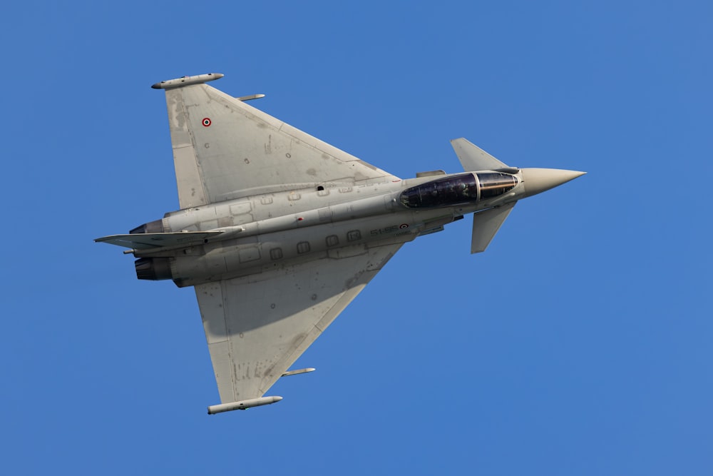 a fighter jet flying through a blue sky