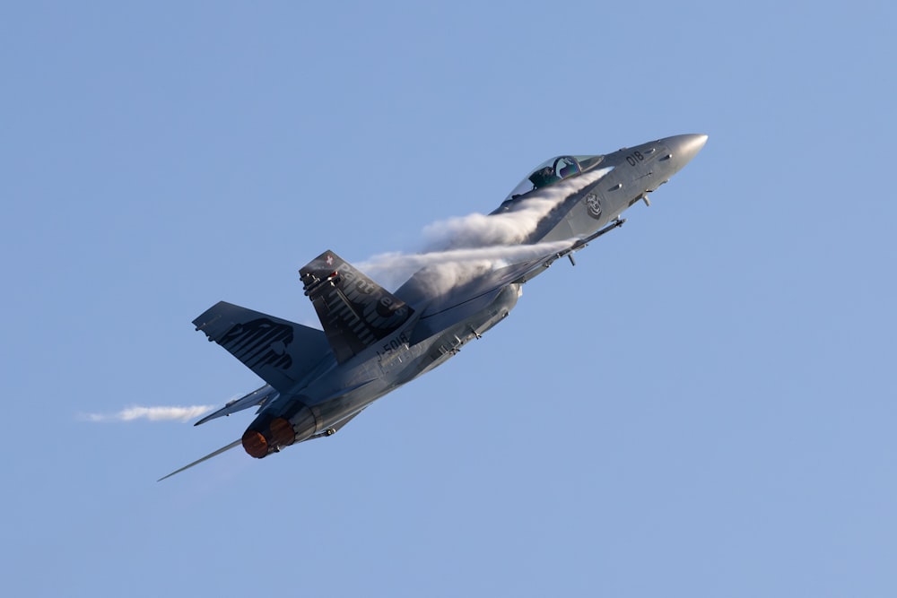 a fighter jet flying through a blue sky