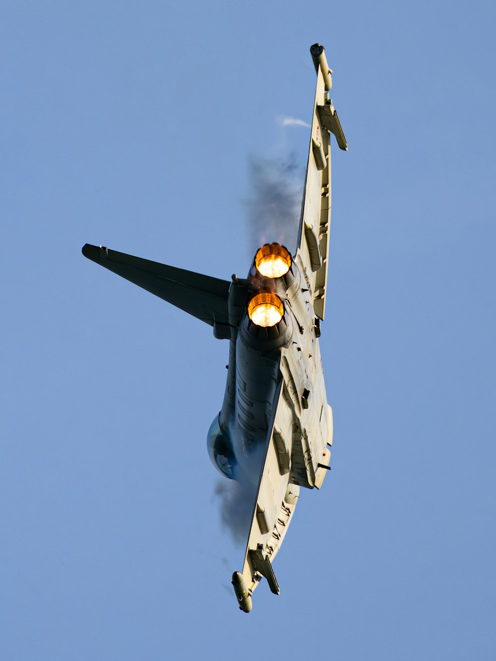 a fighter jet flying through a blue sky