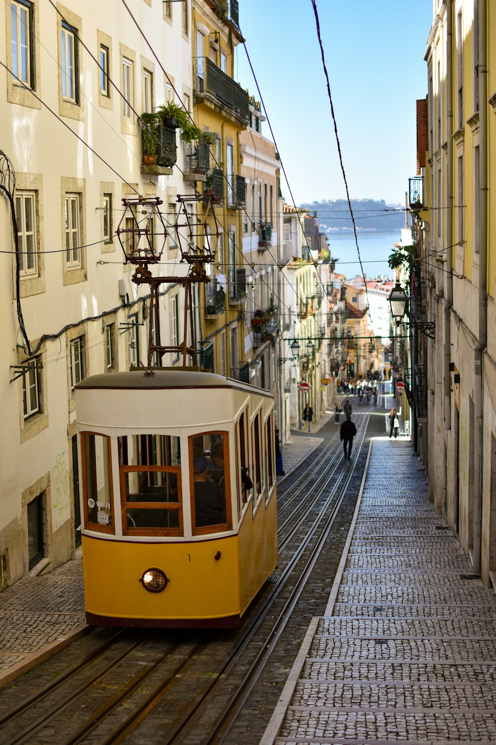 a yellow trolley car traveling down a street next to tall buildings