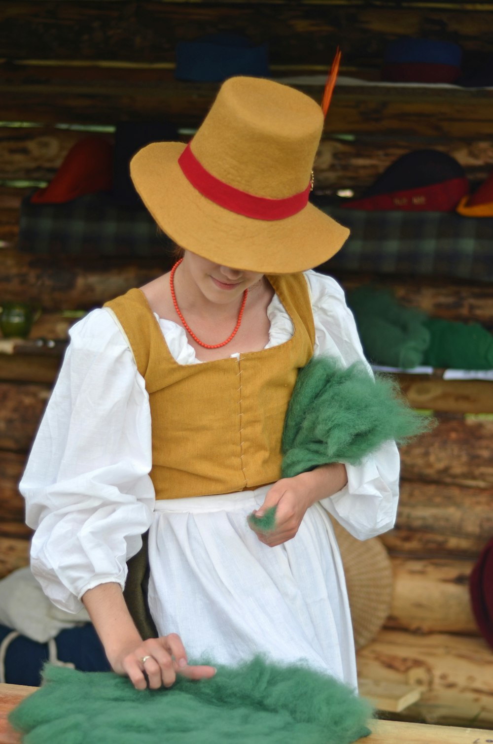 a woman in a dress and hat working on a piece of cloth