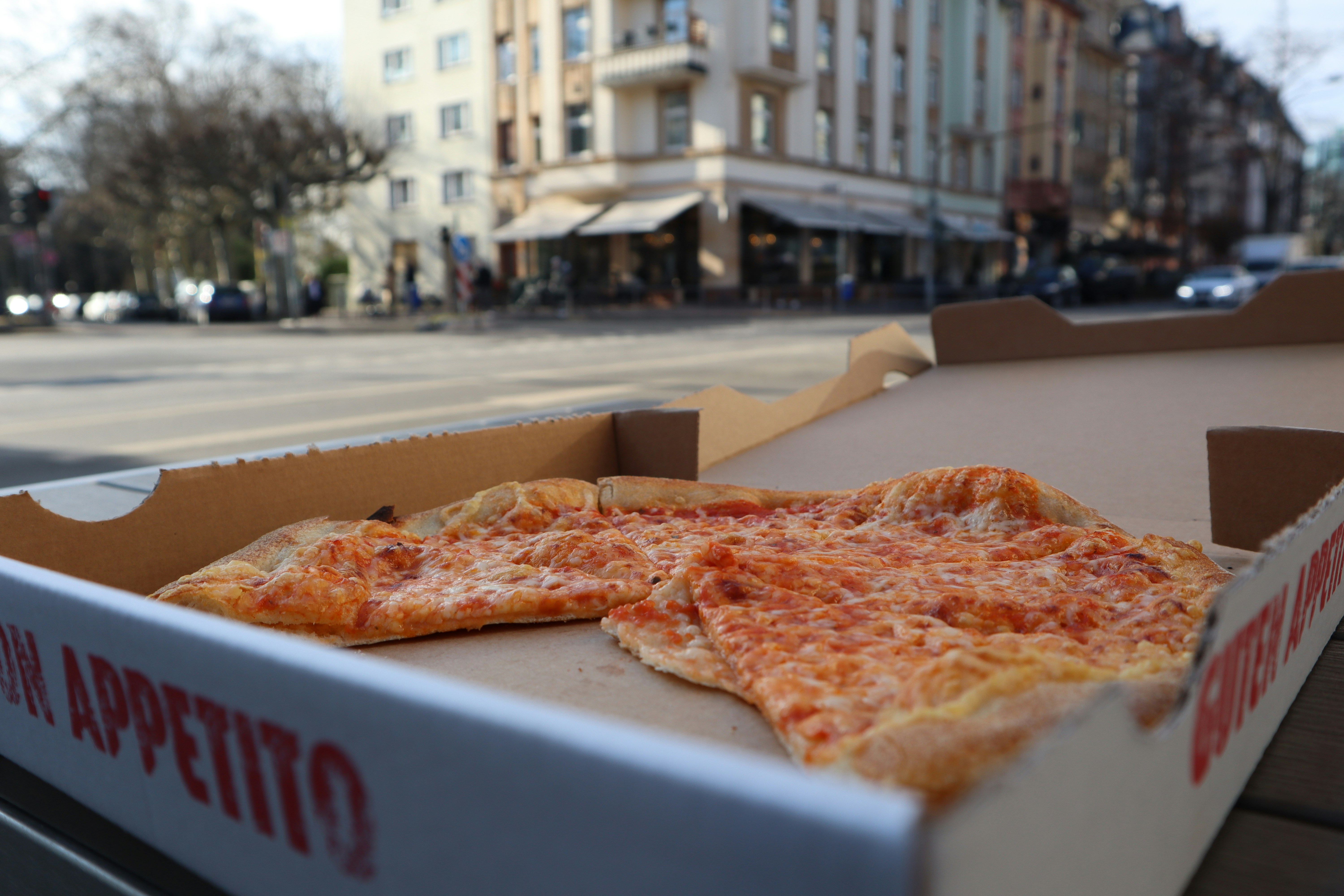 a pizza in a pizza box on a bench