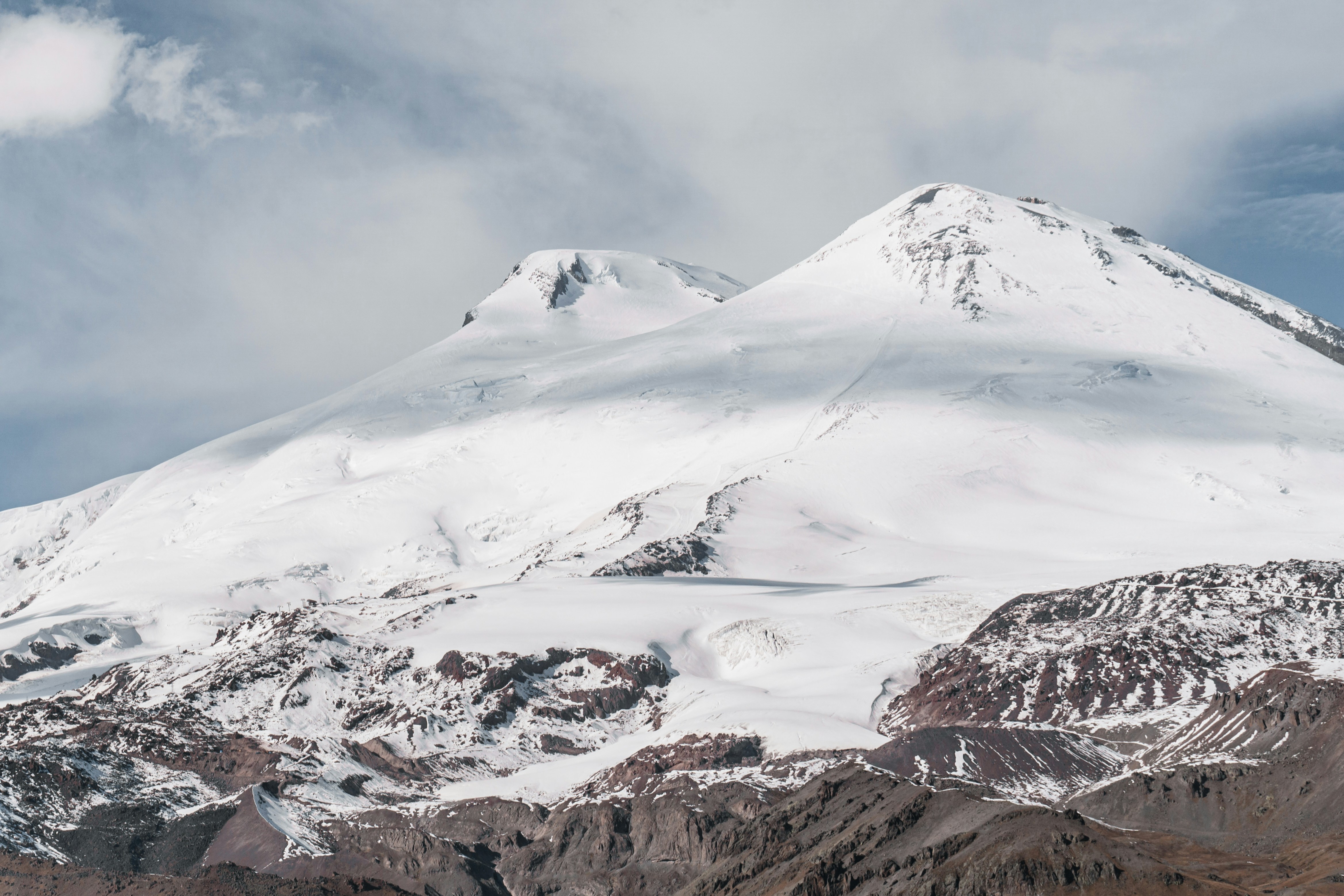 a mountain covered in snow under a cloudy sky