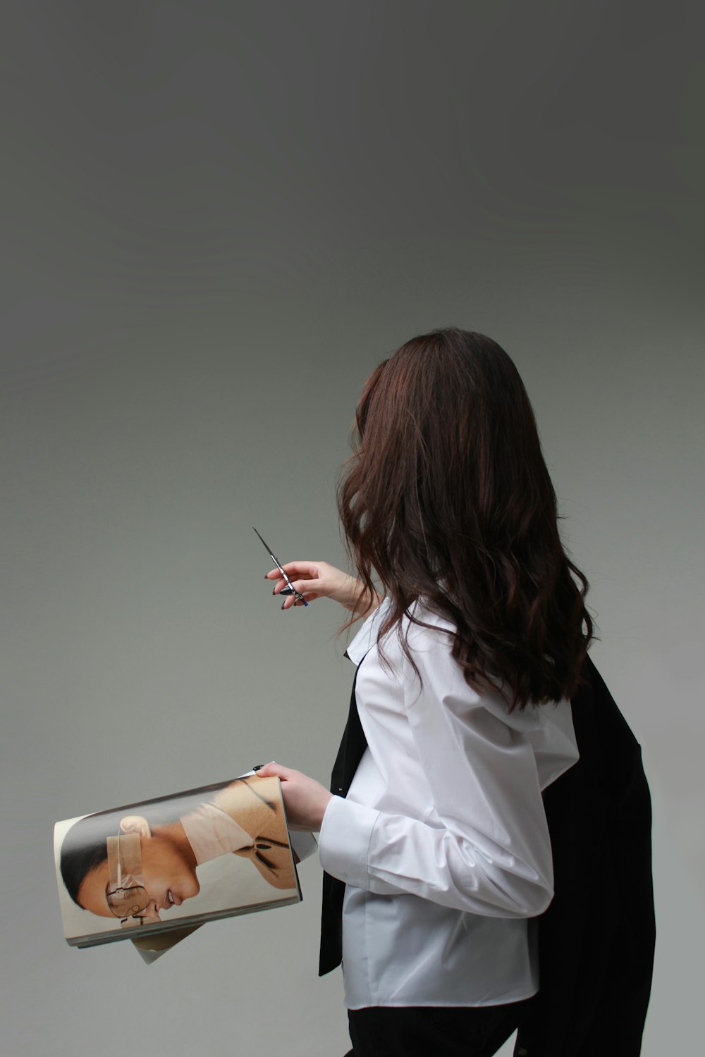 a woman in a white shirt is holding a magazine