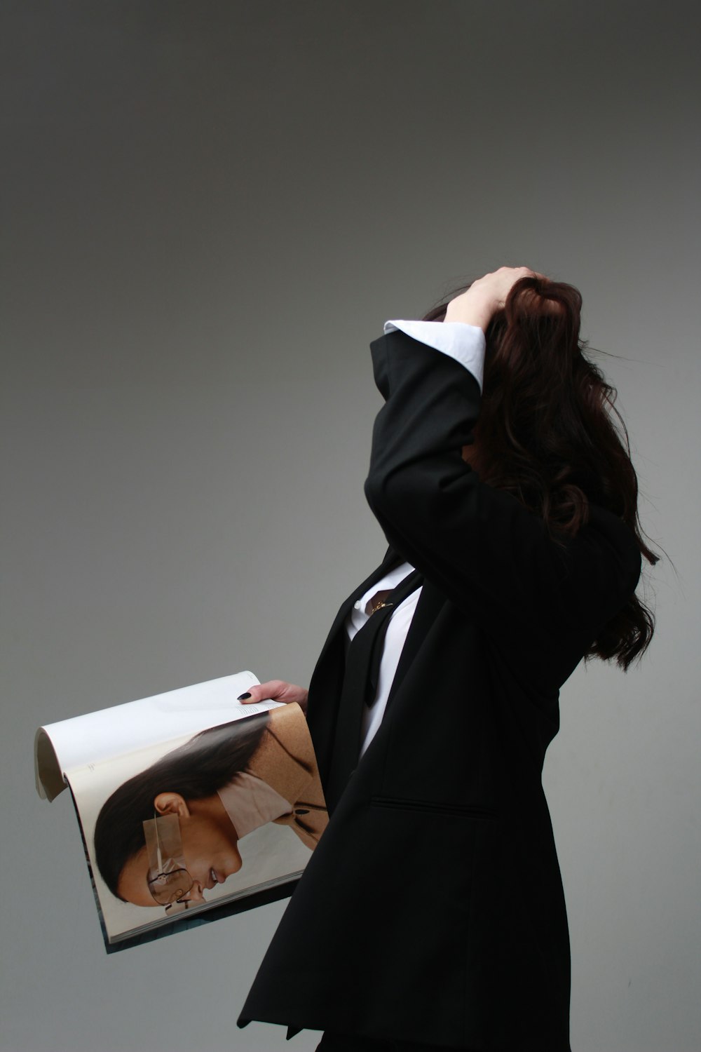 a woman in a suit holding a magazine