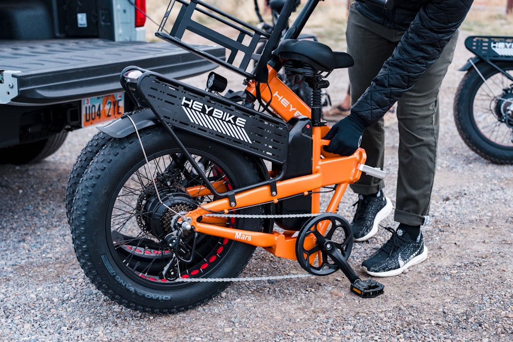 a person standing next to an orange bike