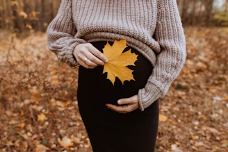 a pregnant woman holding a leaf in her belly