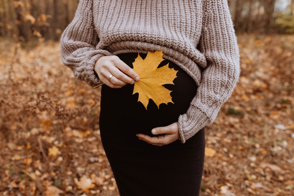 a pregnant woman holding a leaf in her belly