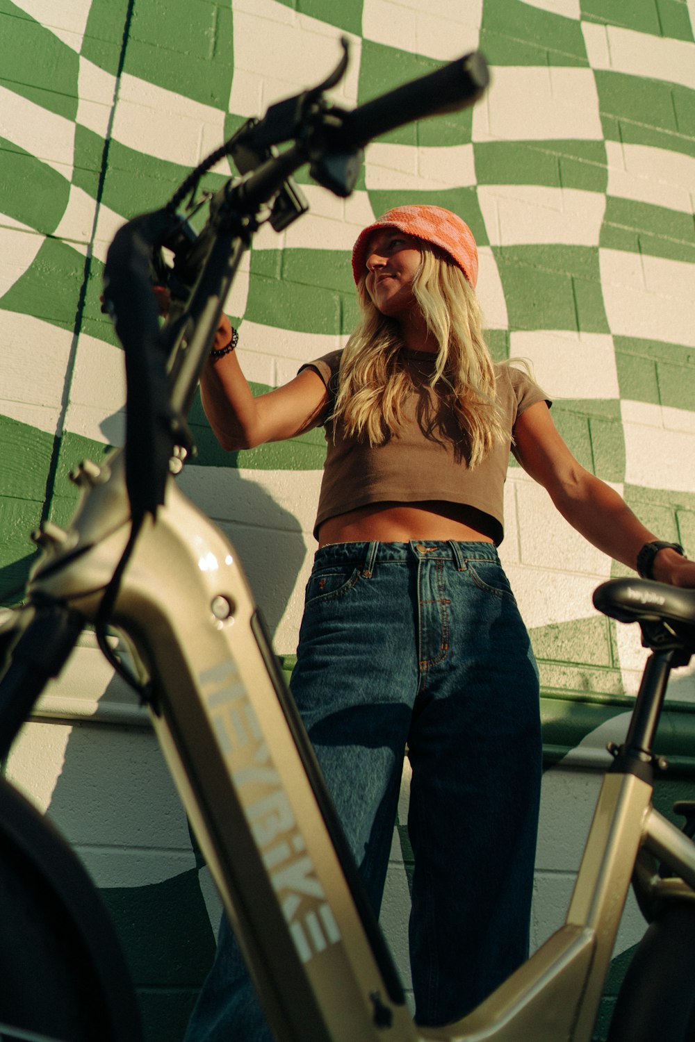 a woman standing next to a bike in front of a checkered wall