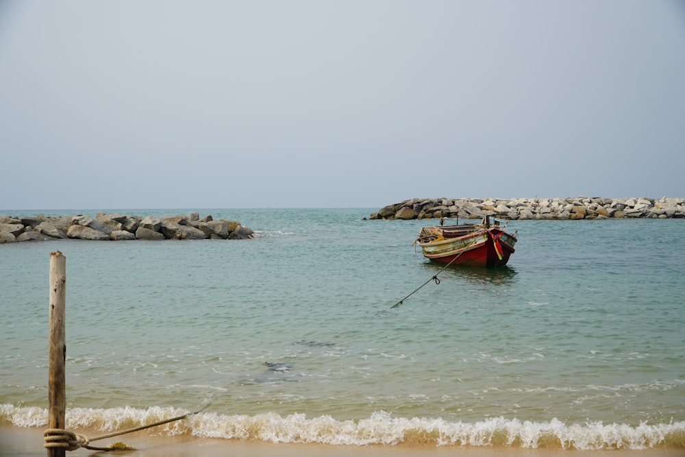 a small boat in the water near a beach