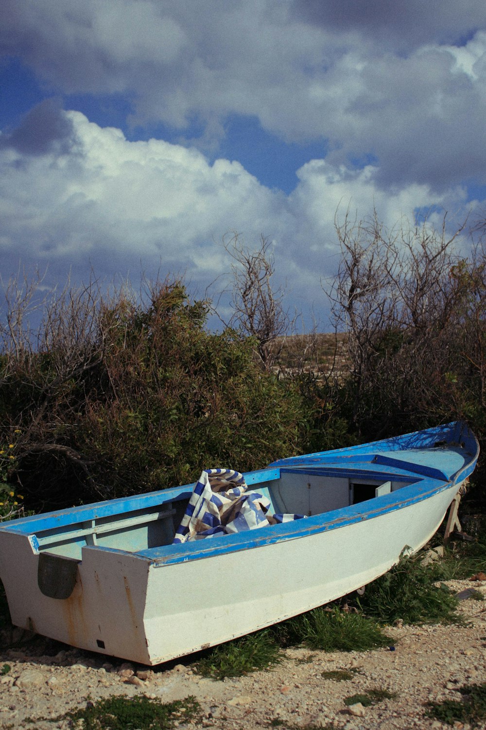 a blue and white boat sitting on top of a sandy beach