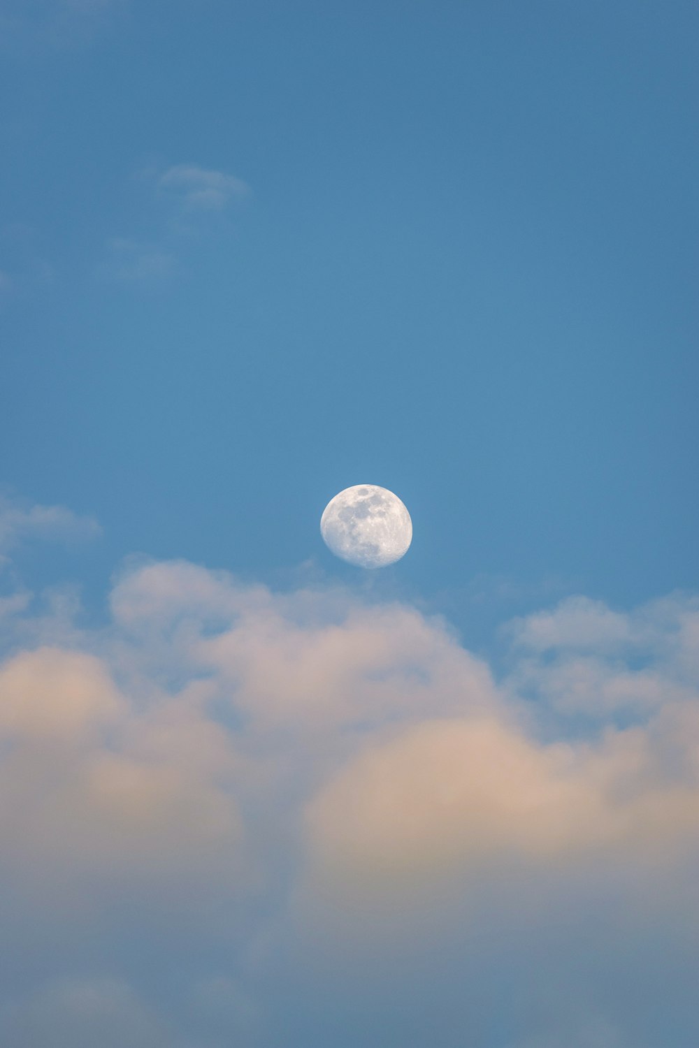 a full moon in a blue sky with clouds