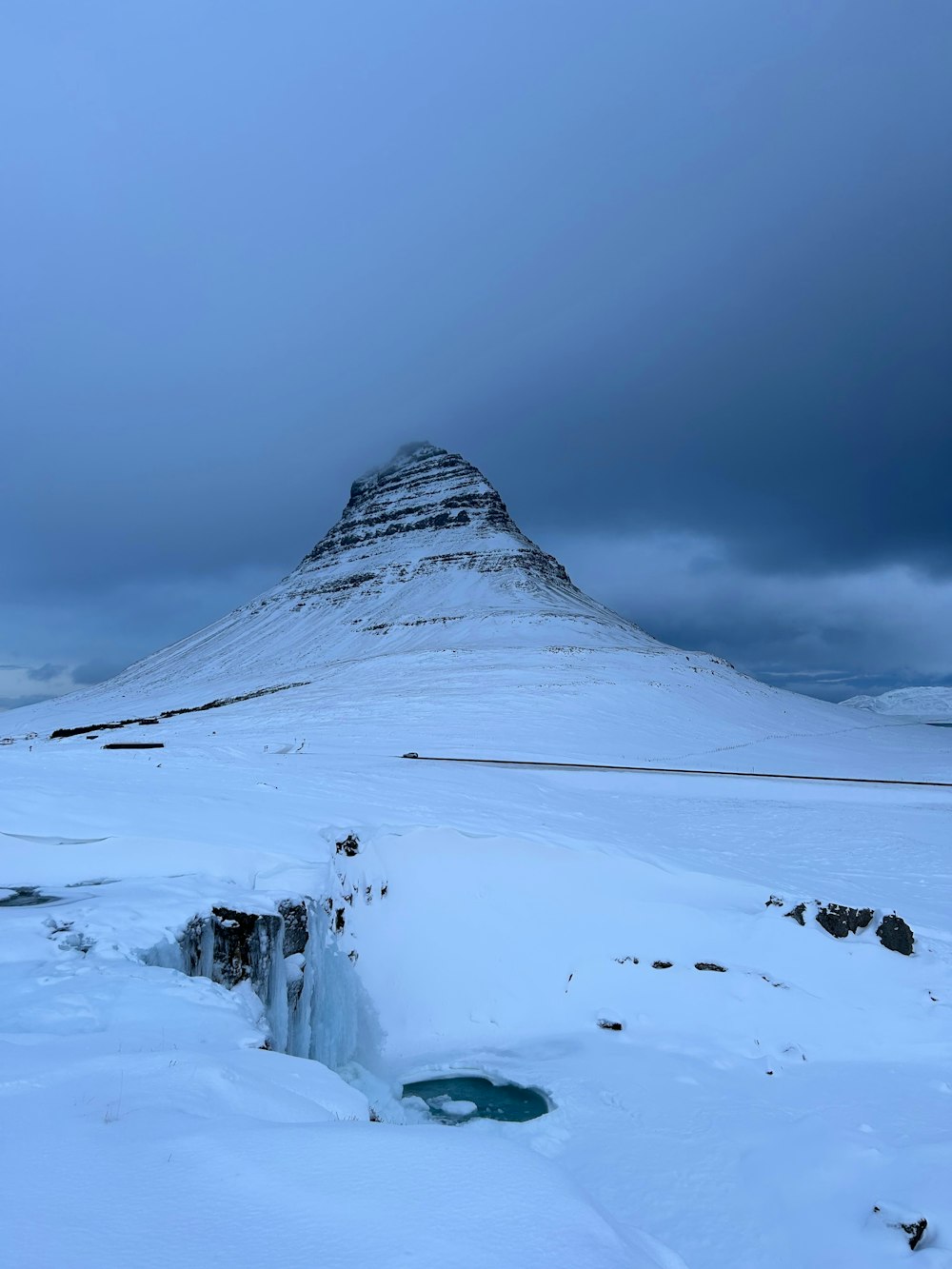 a snow covered mountain with a small pool of water