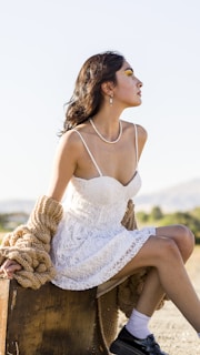 a woman in a white dress sitting on a trunk
