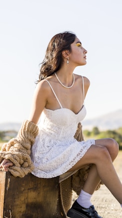 a woman in a white dress sitting on a trunk