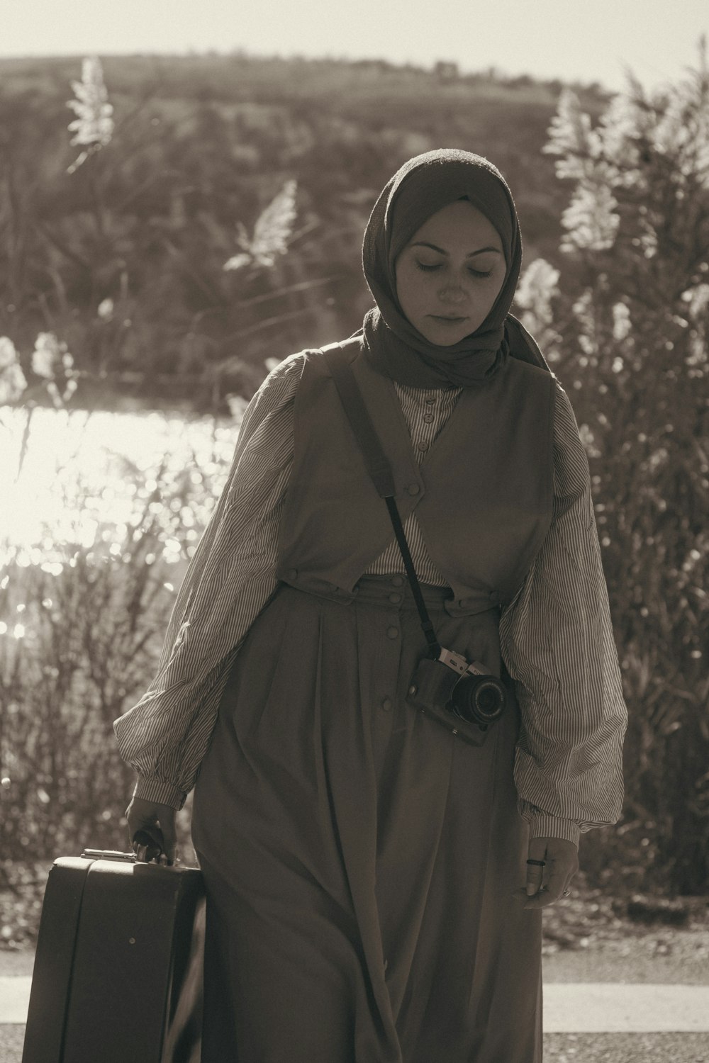 a woman in a hijab carrying a suitcase