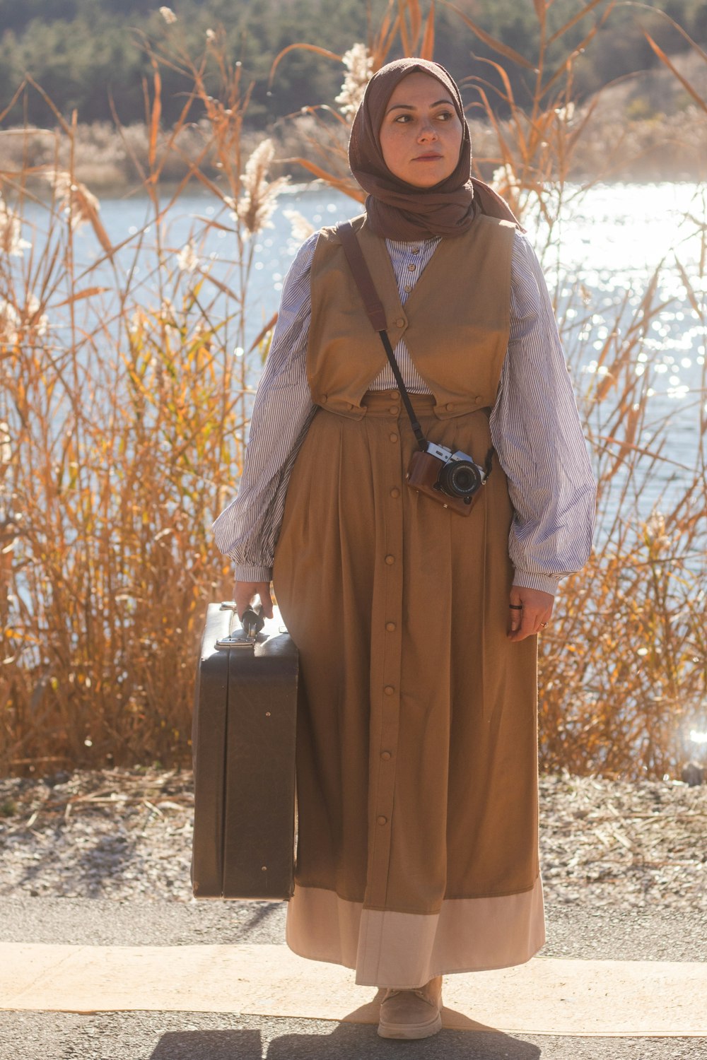 uma mulher em um vestido marrom segurando uma mala