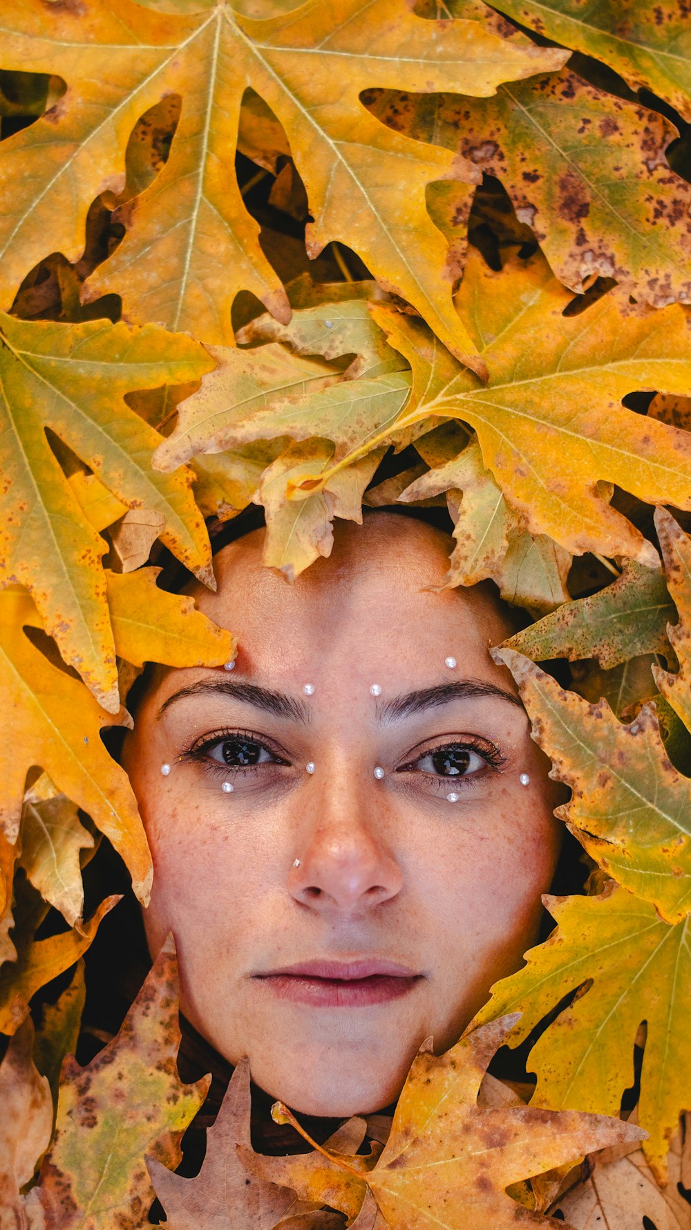 a woman's face is surrounded by leaves