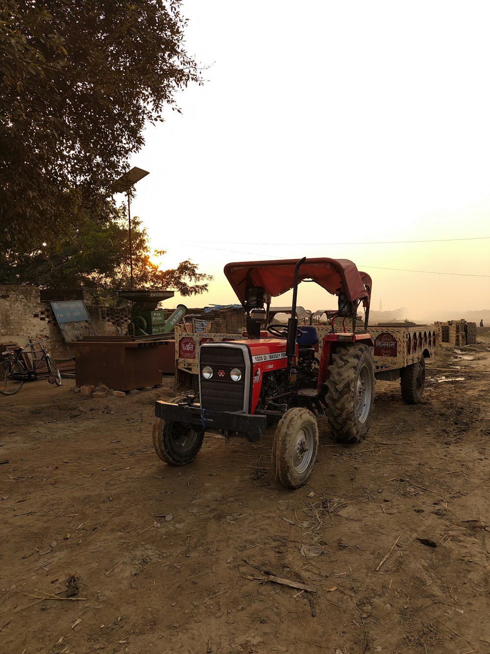 a red tractor parked on top of a dirt field
