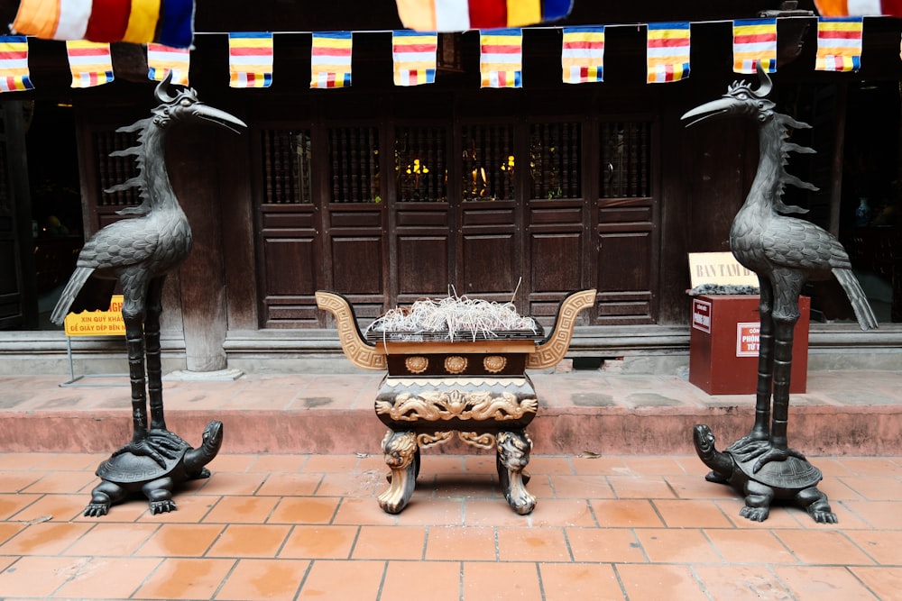 a statue of two birds on a table in front of a building