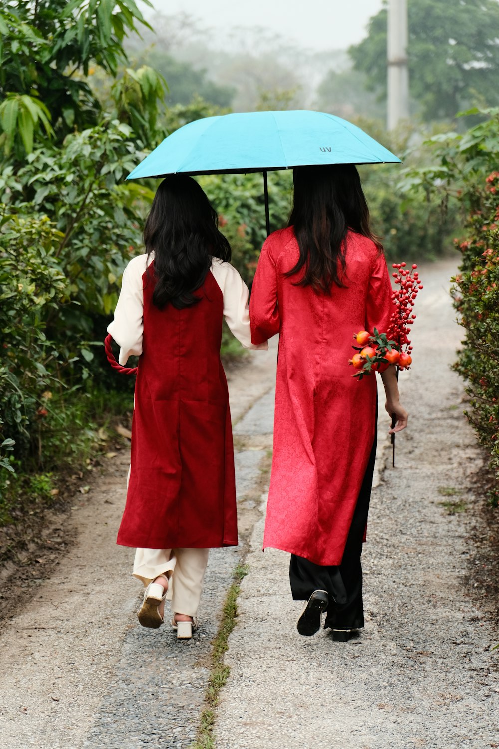 two women walking down a path holding an umbrella