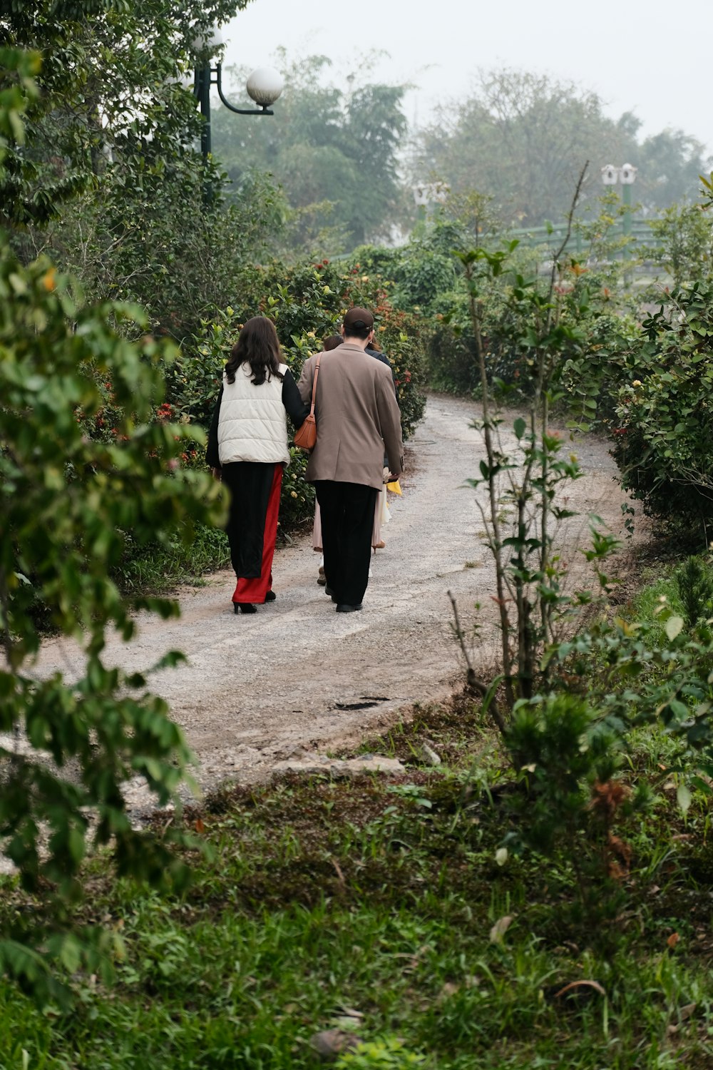 a couple of people walking down a dirt road