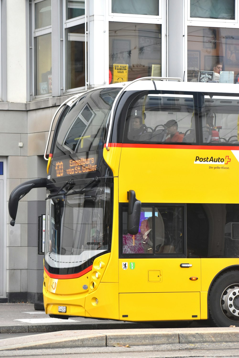 建物の前に停車する黄色い2階建てバス