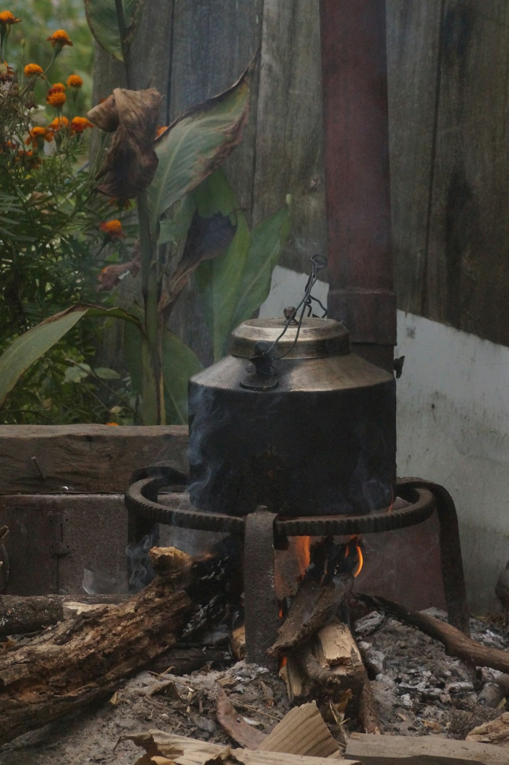 a kettle sitting on top of a stove next to a pile of wood