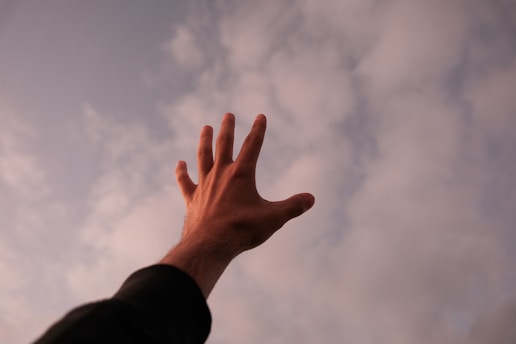 a person's hand reaching up into the sky